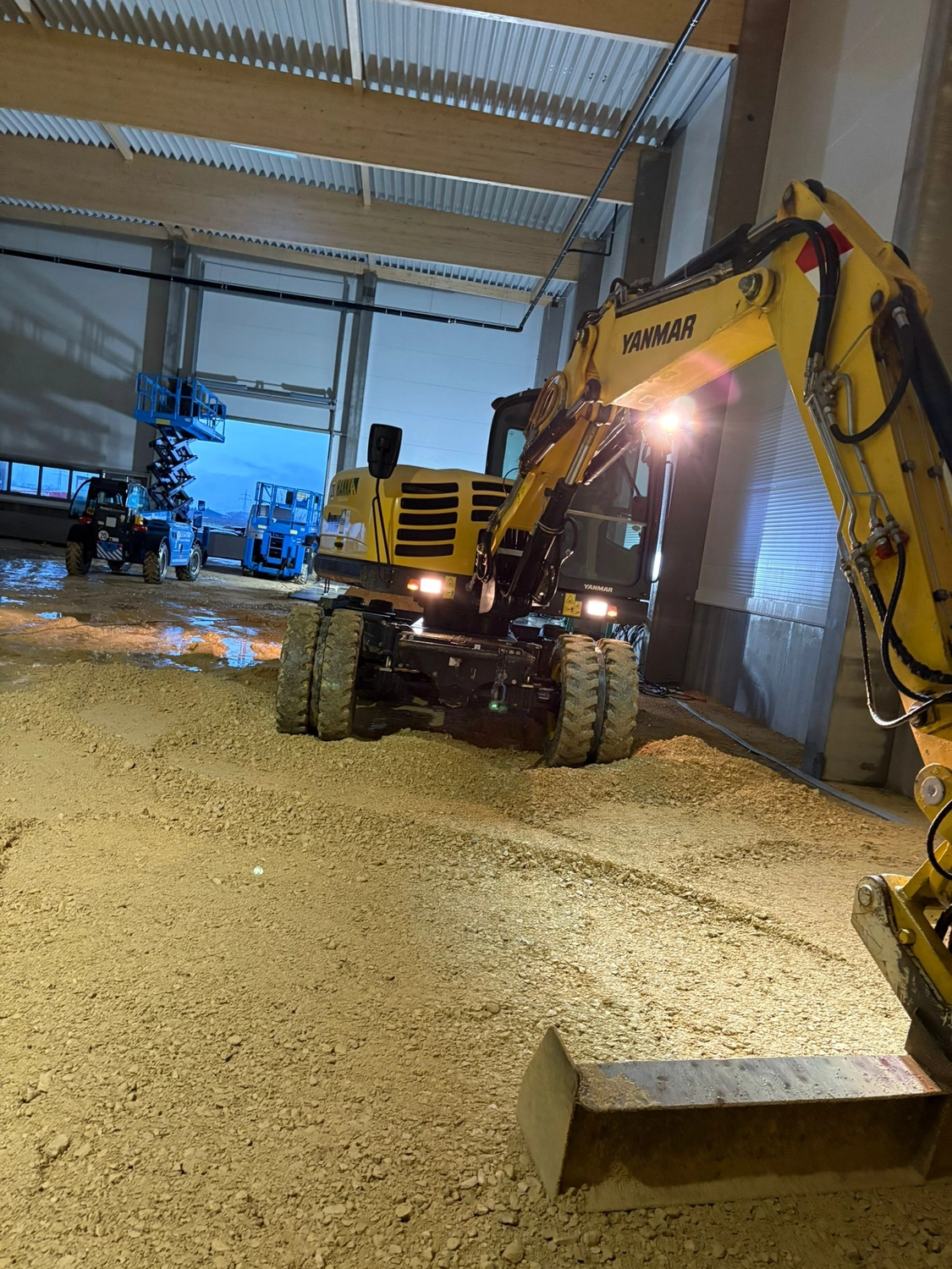 Gartenbau Brandenburg – Gartenbau – Das Bild zeigt einen Yanmar B95W Mobilbagger. Dieses Modell ist eine kompakte Maschine mit kurzem Heck, die für ihre Stabilität und Vielseitigkeit in verschiedenen Baustellenbereichen bekannt ist.